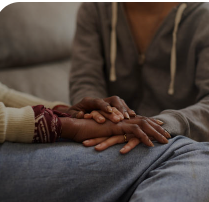 One person gently resting their hands on another's in reassurance